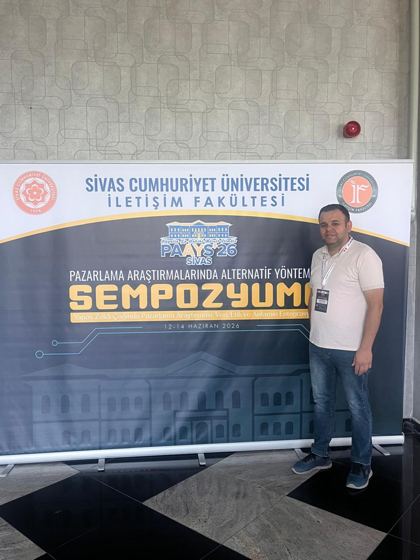 PAAYS'26 sempozyum pankartı önünde